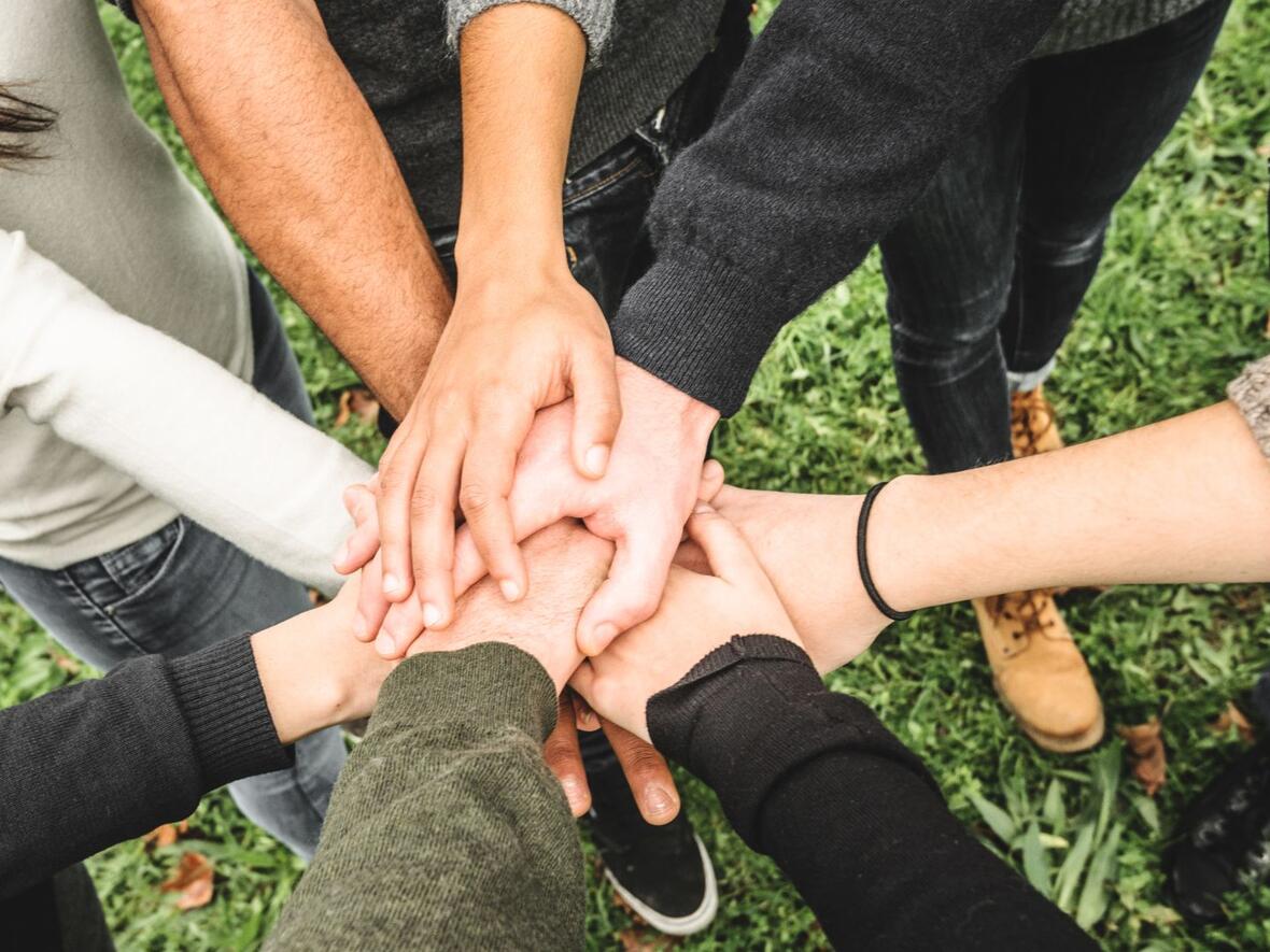 Eine Gruppe von Menschen die ihre Hände in die Mitte des Kreises halten